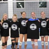 Students wearing and holding up championship shirts from a women's volleyball tournament